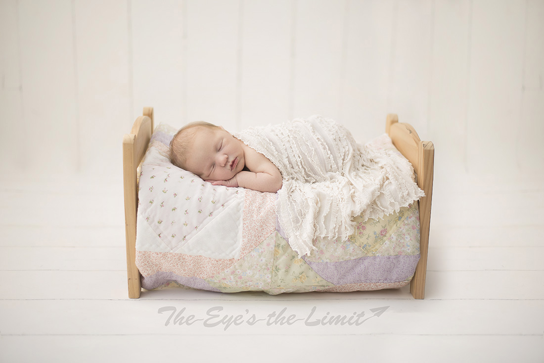 New baby in doll bed sleeping on quilt