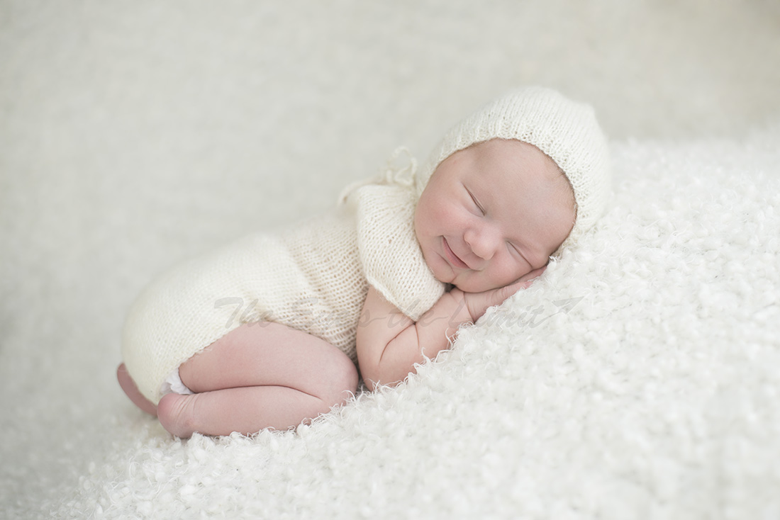 smiling newborn baby cream outfit and background